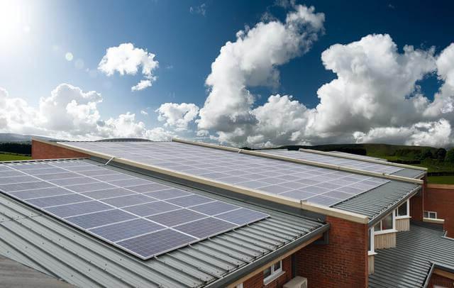 Solar panels on school roofs, with blue sky and clouds above